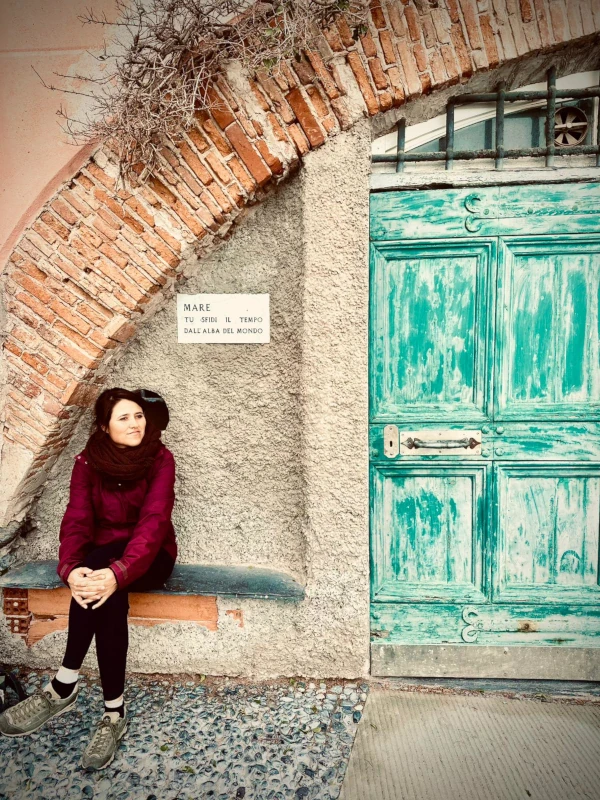 Stefania Mastroianni seduta accanto a una porta di legno turchese